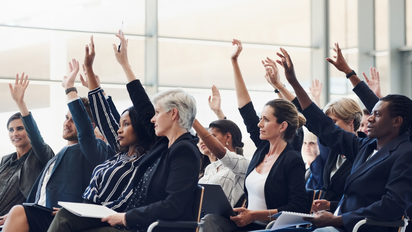 people in a business setting raising their hands